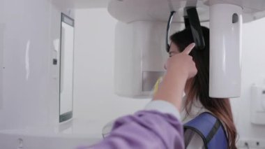 Kafkasyalı bir dişçi, laboratuardaki hasta bir kadına teknolojik bir aletin diş röntgenini gösteriyor. Dişlerini kontrol et. Doktor bey. Diş, tıbbi ve diş tarama testleri mevcut.