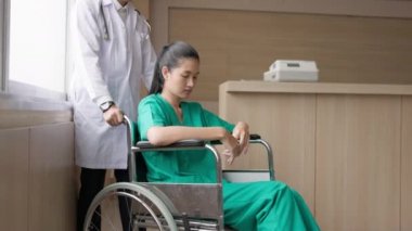 Hastanede tekerlekli sandalyedeki yorgun genç bir kadın gözlerini ve gözyaşlarını kapatıyor. Doktor ona güvence verdi ve yardıma ihtiyacı olup olmadığını sordu..