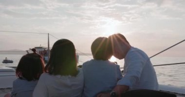 An Asian family is having a good time. Spending time on a yacht at sunset is a wonderful way to unwind.