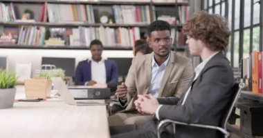 Ofisteki iki erkek iş arkadaşı iş yerinde sohbet ediyor ve birlikte çalışıyorlar. Mutlu iş adamları bilgisayar işi projesini tartışıyorlar. Şirket çalışmasında beyin fırtınası yapıyorlar.