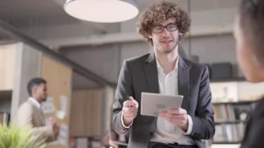 Ofiste, çok ırklı genç erkek ve kadın iş arkadaşlarından oluşan bir grup sohbet ediyor ve iş tartışıyorlar. Kafkas bir adam çalışma yerinde oturuyor, tablet bir bilgisayarın yardımıyla..