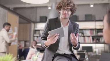 Ofiste, çok ırklı genç erkek ve kadın iş arkadaşlarından oluşan bir grup sohbet ediyor ve iş tartışıyorlar. Kafkas bir adam çalışma yerinde oturuyor, tablet bir bilgisayarın yardımıyla..