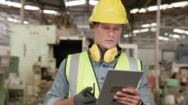 Güvenlik üniforması ve sıkı bir şapka giyen profesyonel bir ağır endüstri mühendisi / işçi tablet bilgisayar kullanır. Bir Afro-Amerikan Endüstrisi