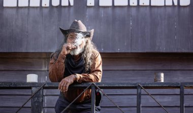 Tütün piposu, geniş kenarlı şapka ve saç bandı takan bir kovboy tarafından içilir..