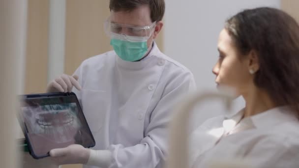 Mladý Zubař Ukazuje Pacientce Zubním Křesle Rentgen Digitálním Tabletu — Stock video