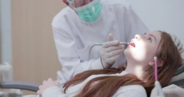 Dişçi muayenehanesine yapılan bir ziyarette dişçi ve asistanı, dişçi koltuğundaki hastayı analiz eder..