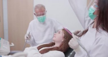 Dişçi muayenehanesine yapılan bir ziyarette dişçi ve asistanı, dişçi koltuğundaki hastayı analiz eder..