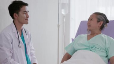 Hastane yatağında bir hastayla konuşan Asyalı bir doktor, bilek kemiğinin röntgenini çeker..