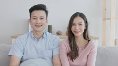 Oturma odasındaki kanepede genç bir çift gülümsüyor..