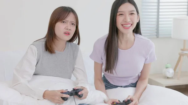 一对有趣的年轻女子一起拿着控制器和玩电子游戏 有几个女人在玩游戏 其中一个是为了赢得这轮比赛而作弊 有趣的电子游戏概念 — 图库照片