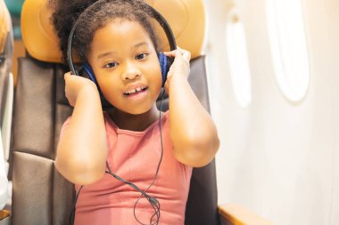 Kızlar uçağın penceresinden dışarı bakıyor. Tatil uçuşu sırasında, bir çocuk neşeyle pencereden dışarı bakar..