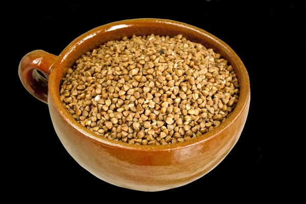 Buckwheat in ceramic bowl on black — Stock Photo, Image