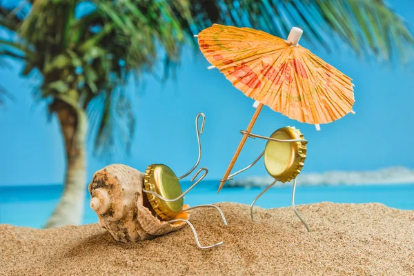 Spielzeugmänner aus Bierdeckeln ruhen sich am Sandstrand aus — Stockfoto