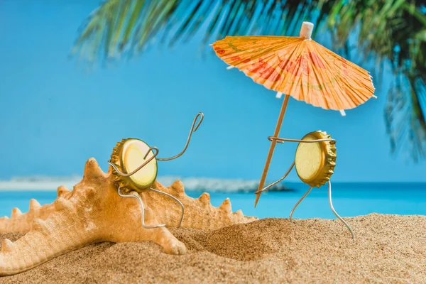 Іграшкові чоловіки з пивних кепок відпочивають на піщаному пляжі — стокове фото