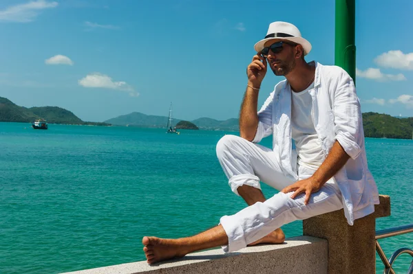 흰색 양복과 모자 바다 바에 바위에 앉아 있는 남자 — 스톡 사진