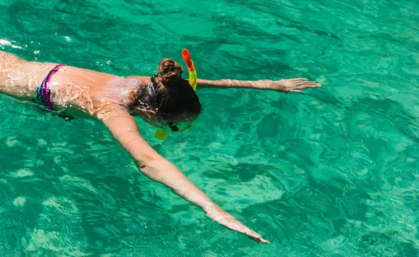 Девушка плавает в море в маске и с трубкой — стоковое фото