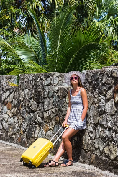 Menina com uma mala amarela em um resort — Fotografia de Stock