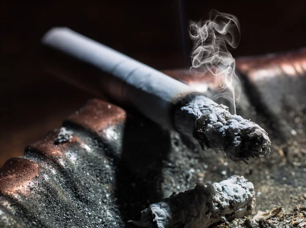 El humo que emite el cigarrillo ardiendo en un cenicero — Foto de Stock