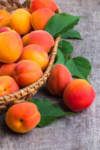 Abricots avec feuilles sur une vieille table en bois — Photo