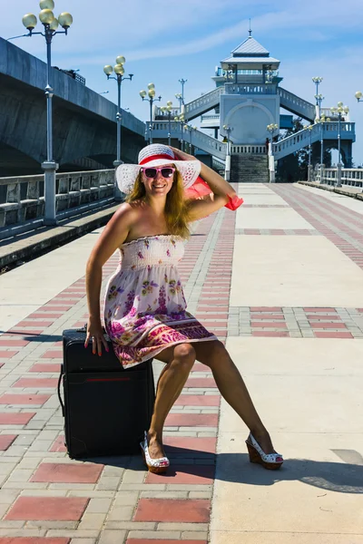 Menina de chapéu com uma mala em repouso — Fotografia de Stock