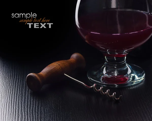 Copa de vino y un sacacorchos sobre una mesa negra — Foto de Stock