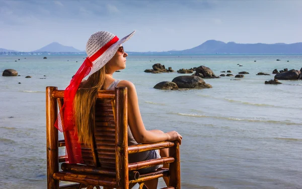 Молода дівчина сидить на стільці біля моря — стокове фото