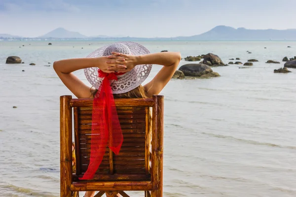 Young girl sitting on a chair near the sea — Stock Photo, Image