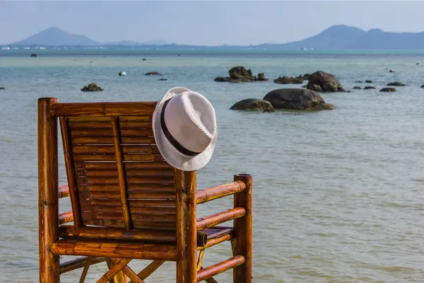 Hatt hänger på en stol på bakgrund av havet — Stockfoto