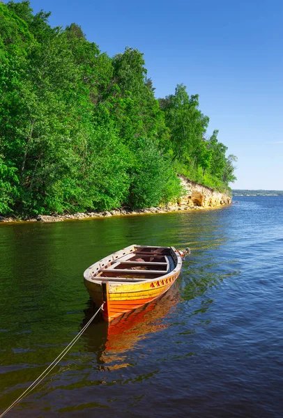 ahşap tekne Nehri üzerindeki banka yansıtan yüzey nehir orman arka plan ve mavi gökyüzü üzerinde.