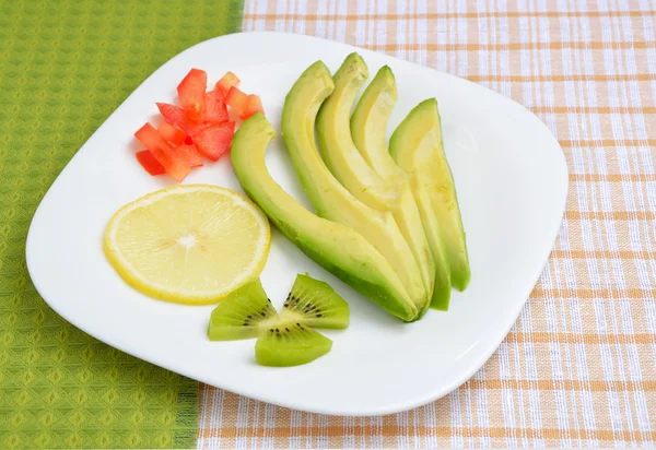 Beyaz bir plaka üzerinde avokado ve limon parçaları — Stok fotoğraf