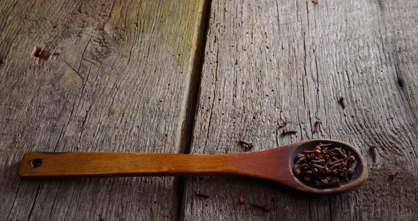 Cuillère en bois avec une gousse. Arrière-plan avec vieilles planches naturelles . — Photo