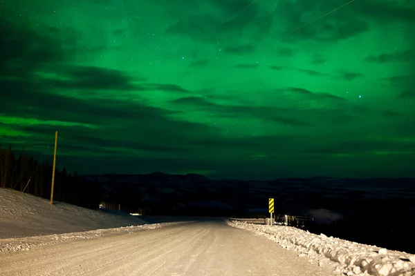 Auroras boreales cielo nocturno sobre carretera rural de invierno —  Fotos de Stock