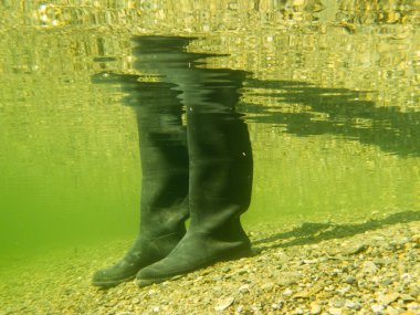 Rubber boots or gumboots underwater on sand ground clipart