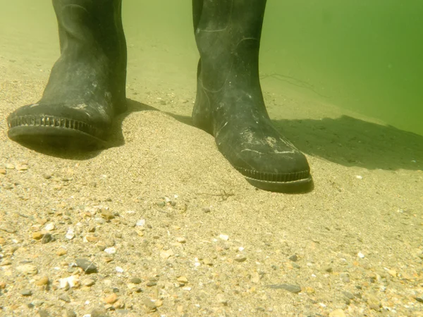 Gummistiefel oder Gummistiefel unter Wasser auf Sandboden — Stockfoto