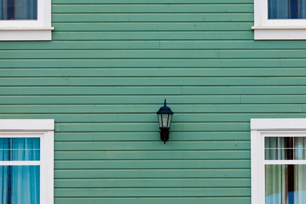 Exterior wall green siding center lamp and windows — Stock Photo, Image