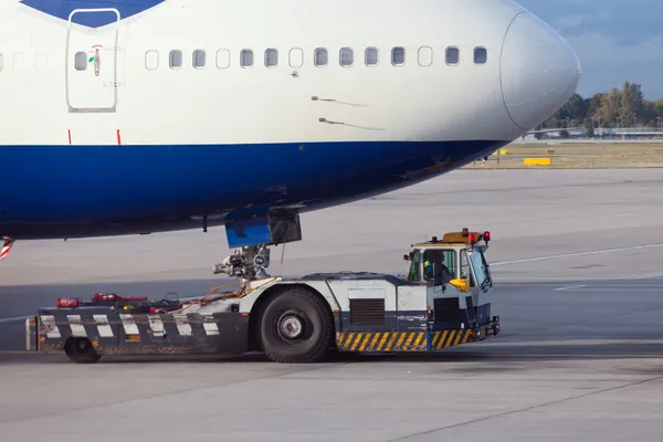 Remorqueur d'avion remorquant un gros avion de ligne pour accoster — Photo