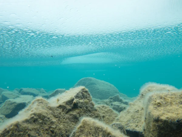 Foglio di ghiaccio copre poco profondo fondo di roccia del lago — Foto Stock