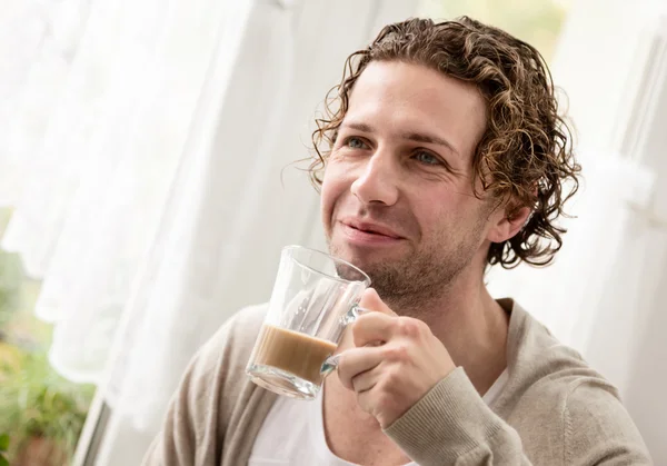 Uomo in piedi vicino a una finestra che beve caffè — Foto Stock