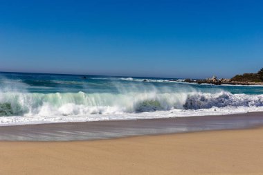 Dalgaları ve mavi gökyüzü olan güzel sahil