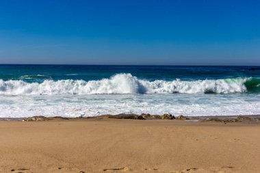 Dalgaları ve mavi gökyüzü olan güzel sahil