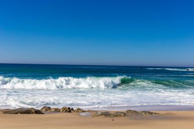 Dalgaları ve mavi gökyüzü olan güzel sahil