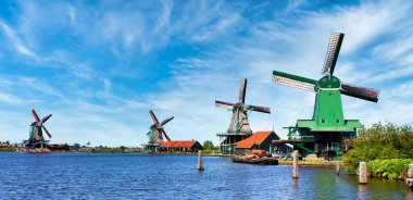 ZAANSE SCHANS, NETHERLANDS - CRCA AĞUSTOS 2020: Hollanda yel değirmeni Amsterdam yakınlarında, mavi gökyüzü ve nehir suyuyla.