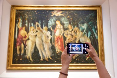 Floransa, İtalya - Temmuz 2021 dolaylarında. Turist Botticelli 'nin fotoğrafını çekiyor - Bahar. Kafkasyalı kadın elleri cep telefonuyla
