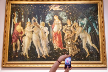 Floransa, İtalya - Temmuz 2021 dolaylarında. Turist Botticelli 'nin fotoğrafını çekiyor - Bahar. Kafkasyalı kadın elleri cep telefonuyla