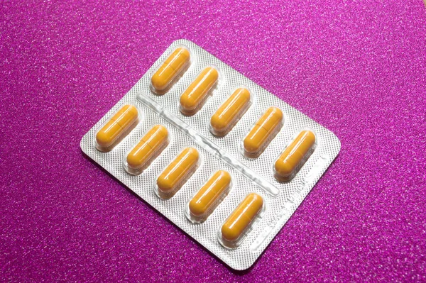 Żółte Kapsułki Tabletki Srebrnym Blistrze Szkarłatnym Tle Zbliżenie — Zdjęcie stockowe