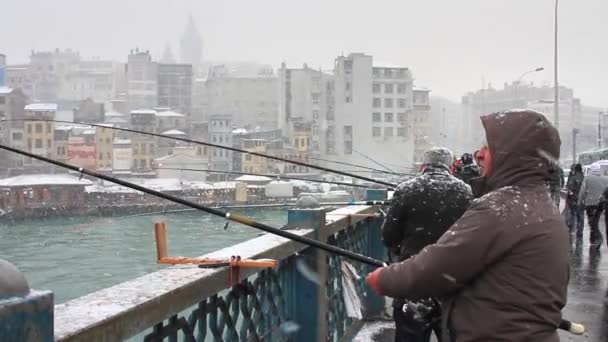 Mens vissen in sneeuwval op galata brug — Stockvideo