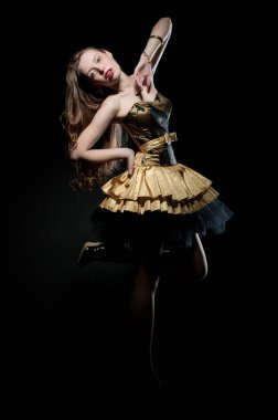 Güzel, seksi esmer kız siyah arka planda poz veriyor. Gece elbisesiyle.