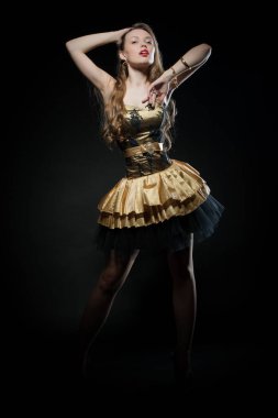 Güzel, seksi esmer kız siyah arka planda poz veriyor. Gece elbisesiyle.