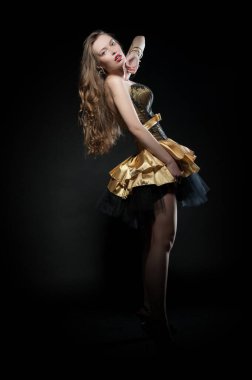 Güzel, seksi esmer kız siyah arka planda poz veriyor. Gece elbisesiyle.