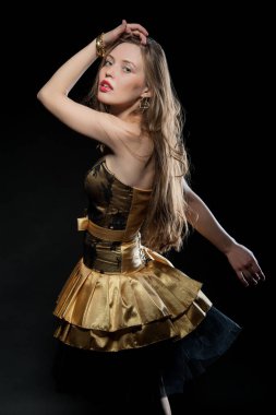 Güzel, seksi esmer kız siyah arka planda poz veriyor. Gece elbisesiyle.